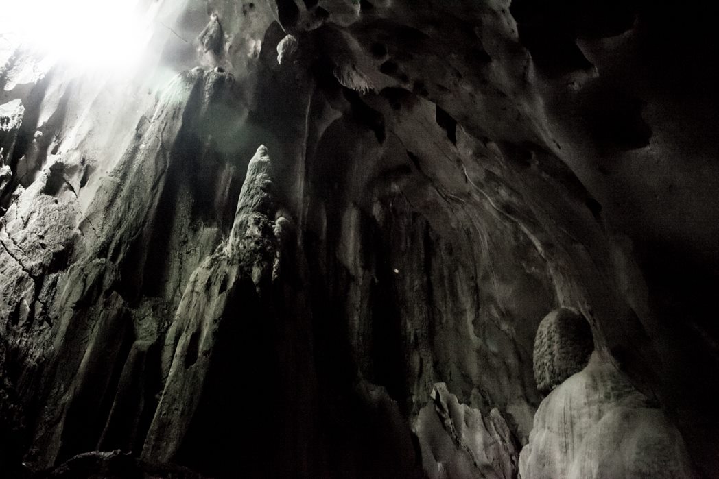 Light beams in dark cave highlighting stalactites in Borneo.