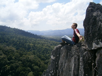 Visitor sitting on top of Batu Punggul overlooking the rainforest