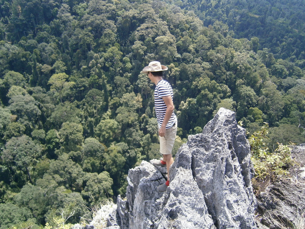 Hiker standing on the limestone summit of Batu Punggul