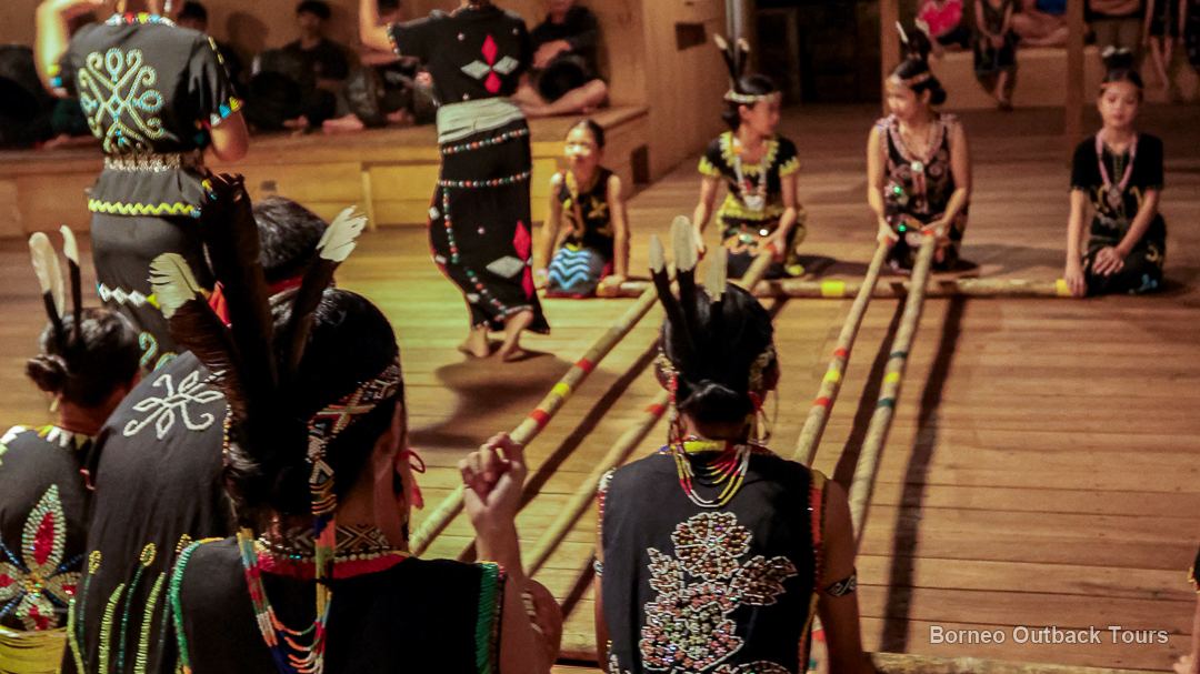 Murut dancers in traditional beaded costume performing the magunatip bamboo dance at a cultural night in Sapulot, Sabah