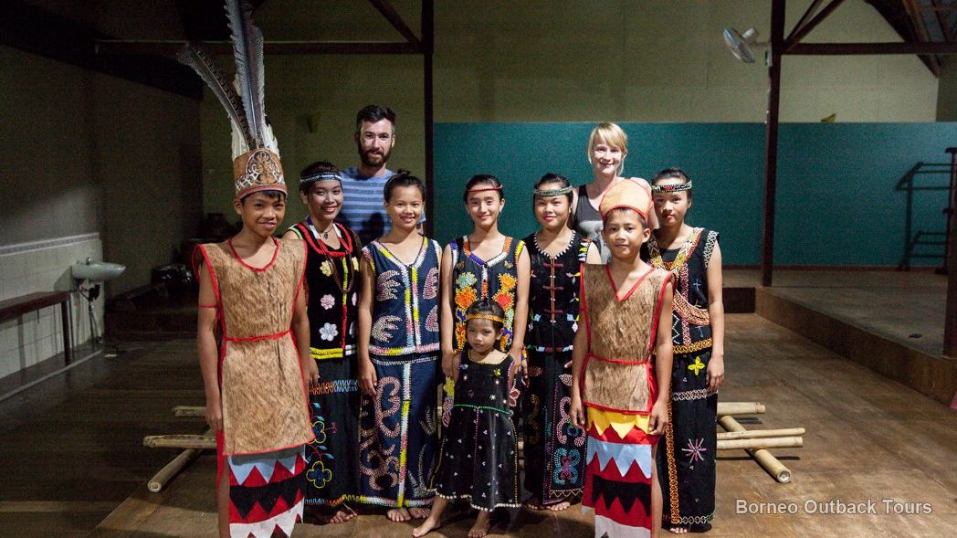 Young Murut people in traditional beaded dress and bark-cloth vests at a longhouse in Sabah's interior