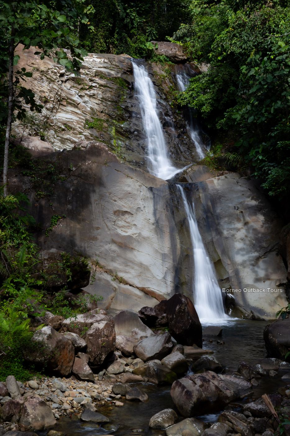 A tall waterfall in lush rainforest during the dry season, the best time to visit Sabah