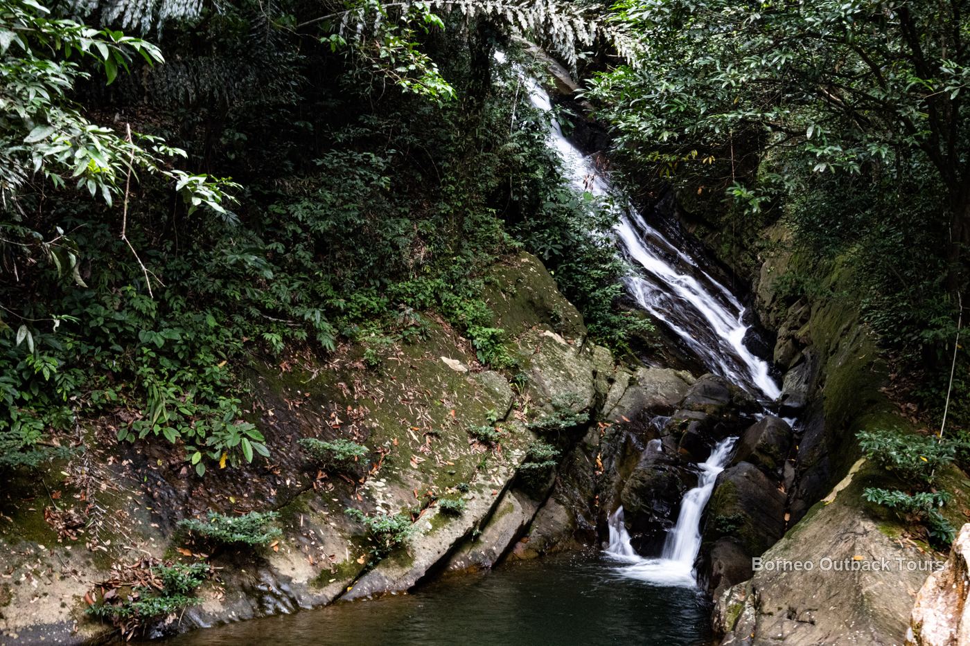 A calm emerald waterfall pool at Vangkaakon in Sapulot, a natural swimming spot for families
